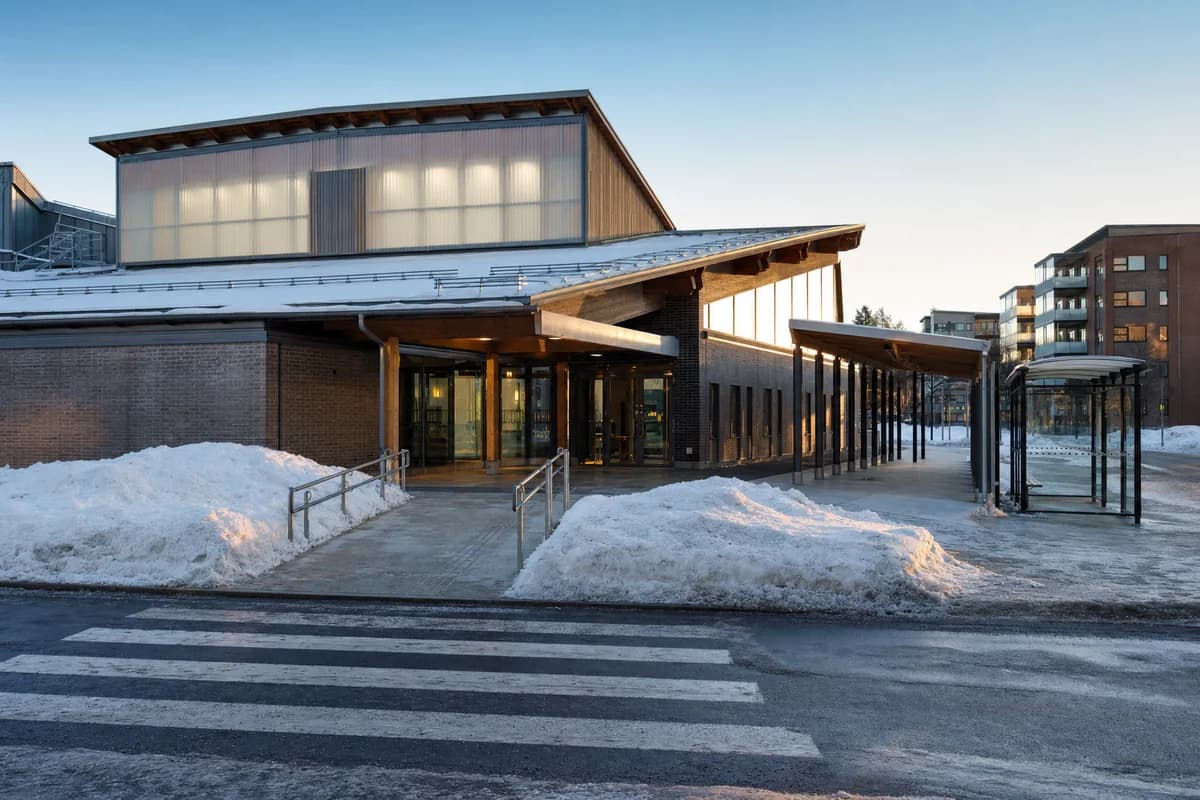 Unoccupied public aquatic center beside an empty winter bus shelter and cleared accessible paths.