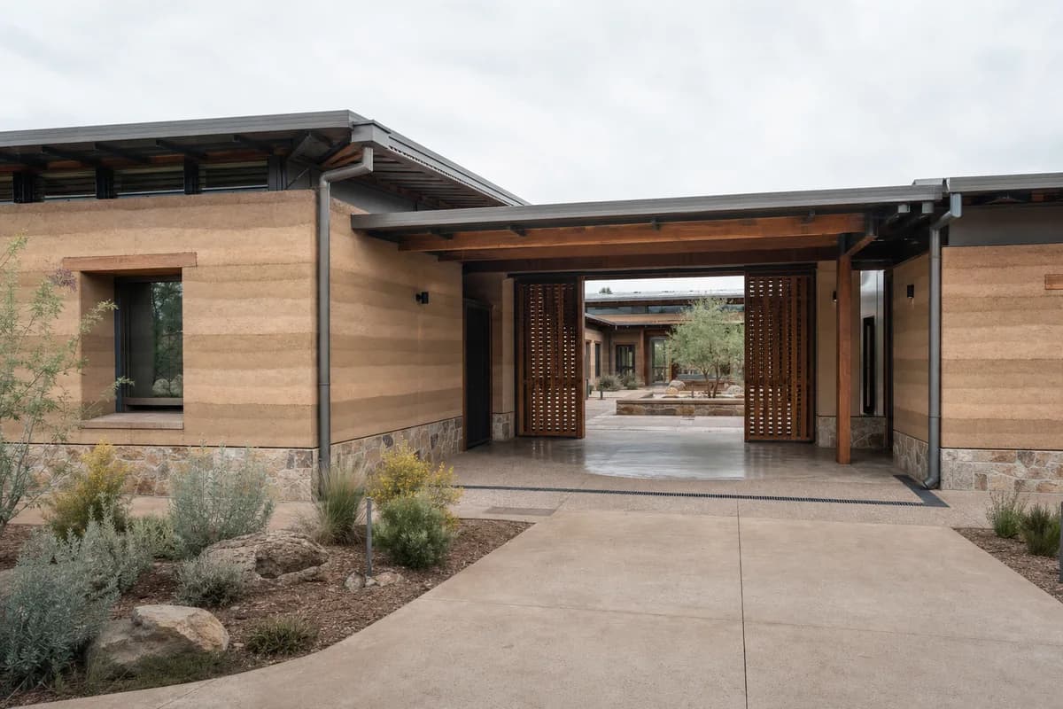 Unoccupied rammed-earth justice center with a shaded court and deeply protected entrance.