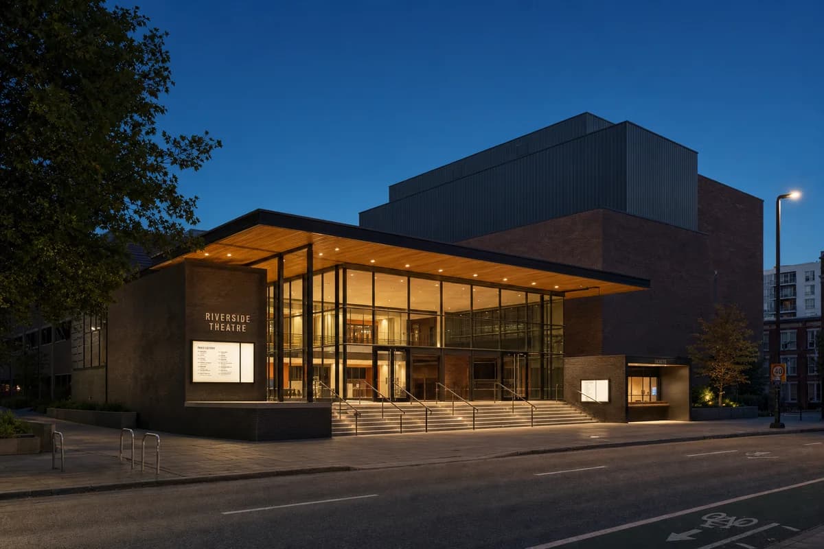 Unoccupied performing arts house with a restrained warm foyer on a dark city street.