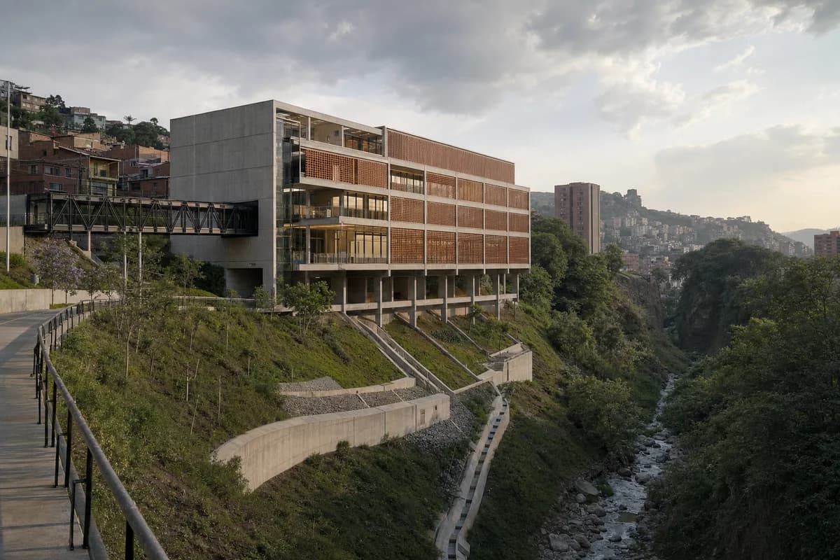 Terracotta-screened public theater at a planted Medellin ravine edge.