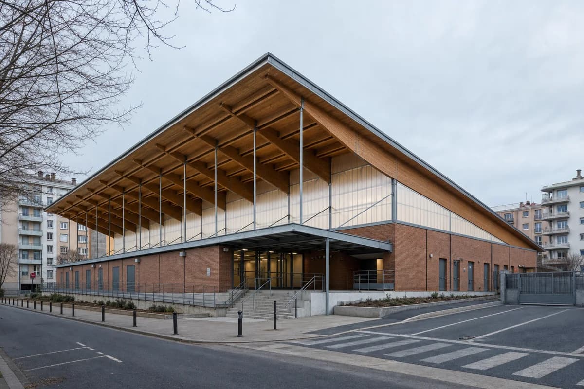 Long-span timber sports hall grounded by a brick neighborhood base.