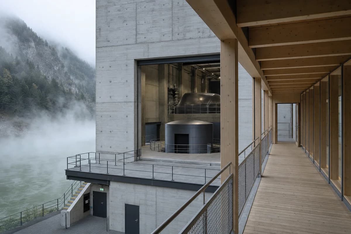 Timber hydropower visitor bridge crossing concrete halls in river fog.
