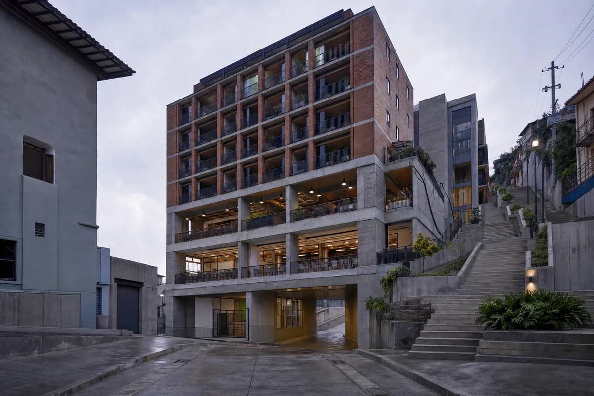 Concrete and brick mixed-use block bridging steep wet streets.