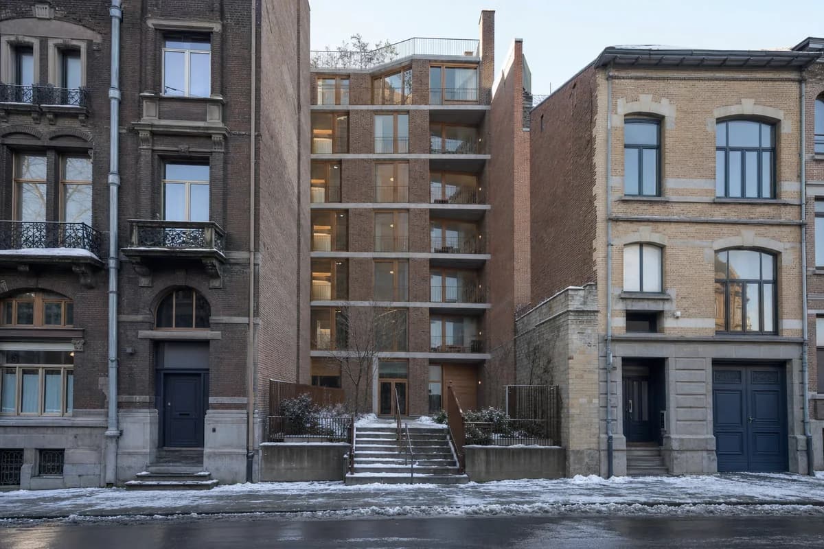 Brick shared-housing infill between irregular winter street facades.