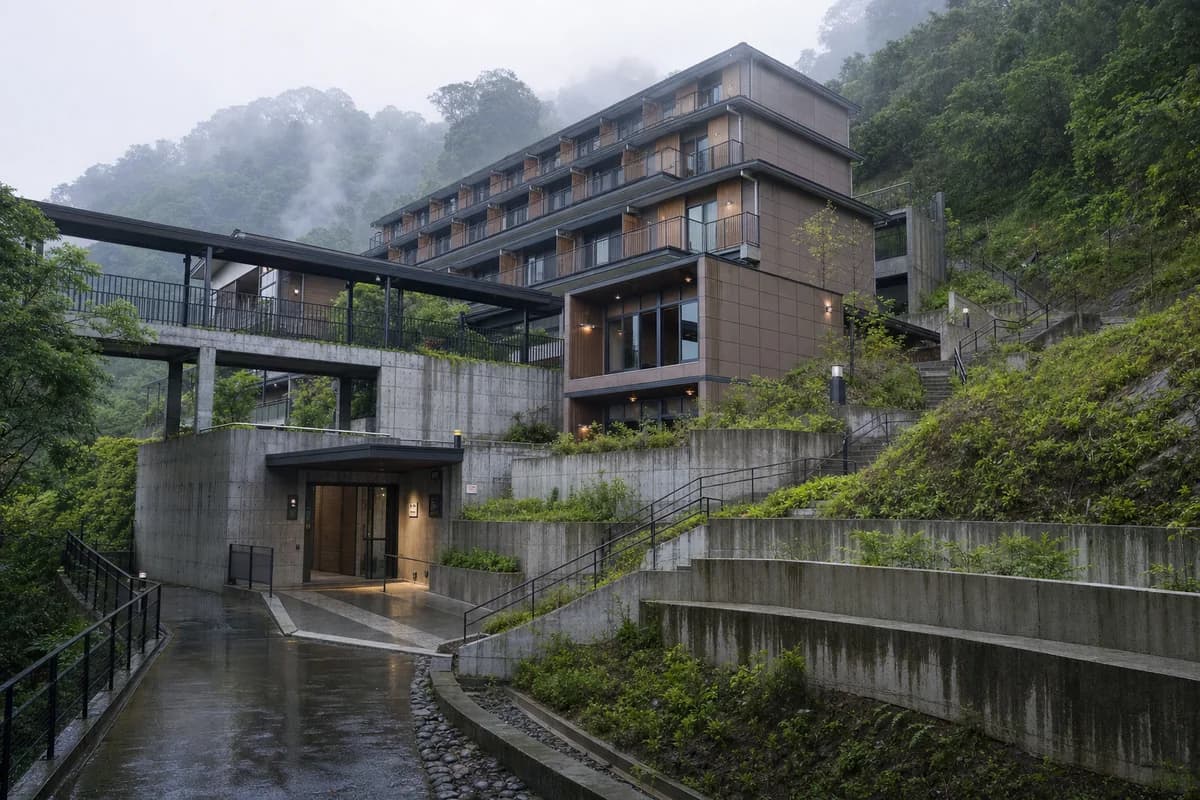 Ceramic and concrete youth hostel emerging from mist on a Taipei hillside.