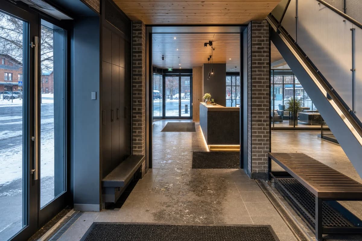 Unoccupied winter hotel lobby with brick piers, slush mats, and a translucent stair.