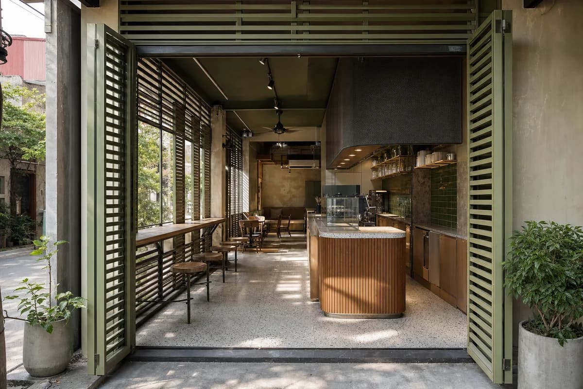 Monsoon Window Cafe, street-edge cafe organized by layered shutters creating a shaded bar and narrow seating ledge.