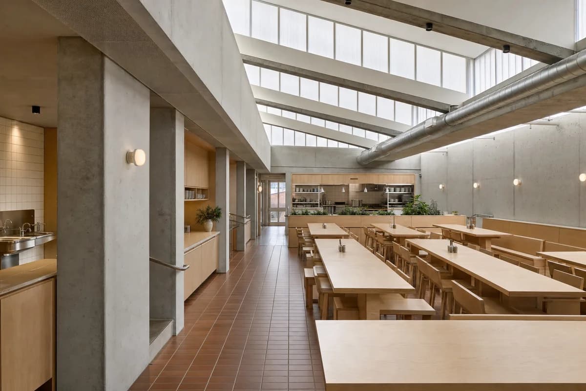 Sawtooth Breakfast Refectory, breakfast refectory organized by three parallel table bays beneath a north-lit sawtooth roof, backed by a closed prep spine.