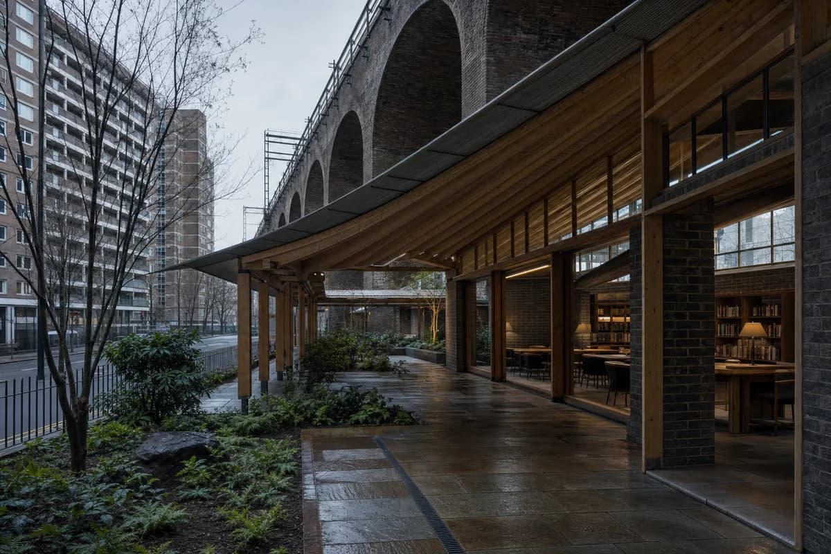 Unoccupied linear winter garden and reading hall beneath an urban railway.