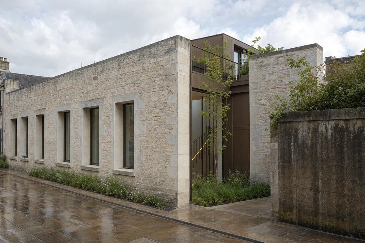 Contemporary terraced house recessed behind a repaired limestone archive facade.