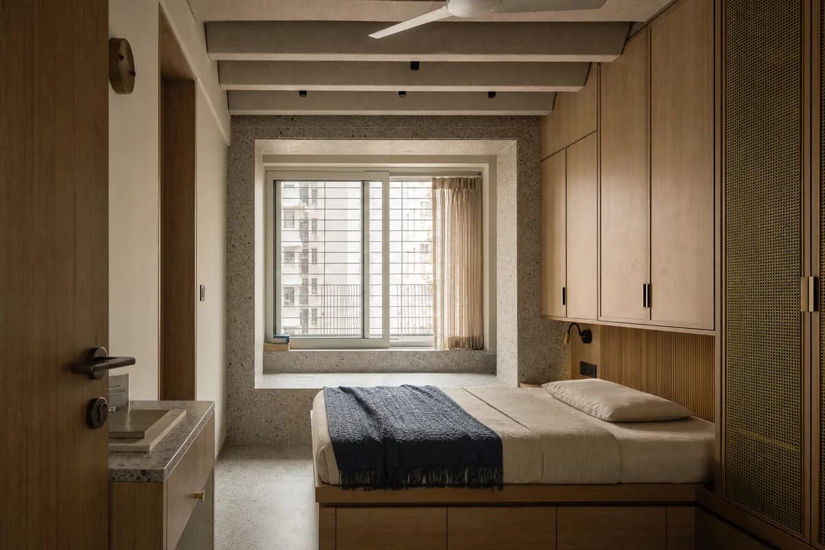 Acoustic City Bedroom, apartment bedroom organized by a deep acoustic window, storage wall, and ceiling baffle controlling noise.