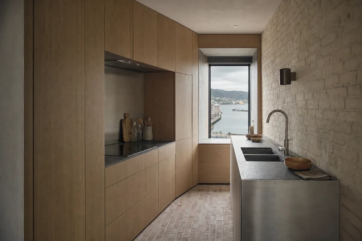 Harbor Apartment Kitchen, compact apartment kitchen shaped by one clearly folded full-height cabinet volume turning to shape the room and frame one controlled harbor view.