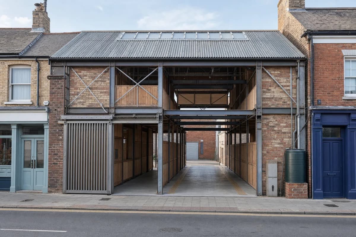 Unoccupied reused-brick market arcade with visible steel connections between quiet shopfronts.