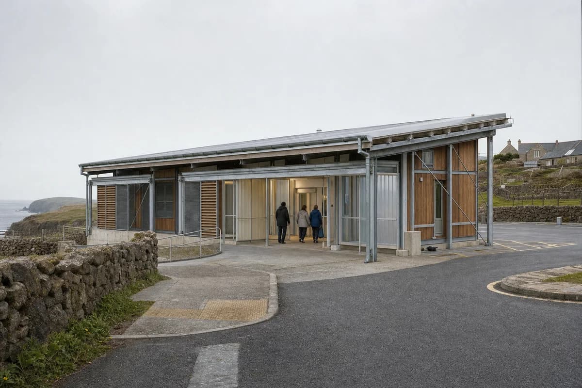 Second accepted render of the same island care hub from the same bus-approach viewpoint in maritime overcast.