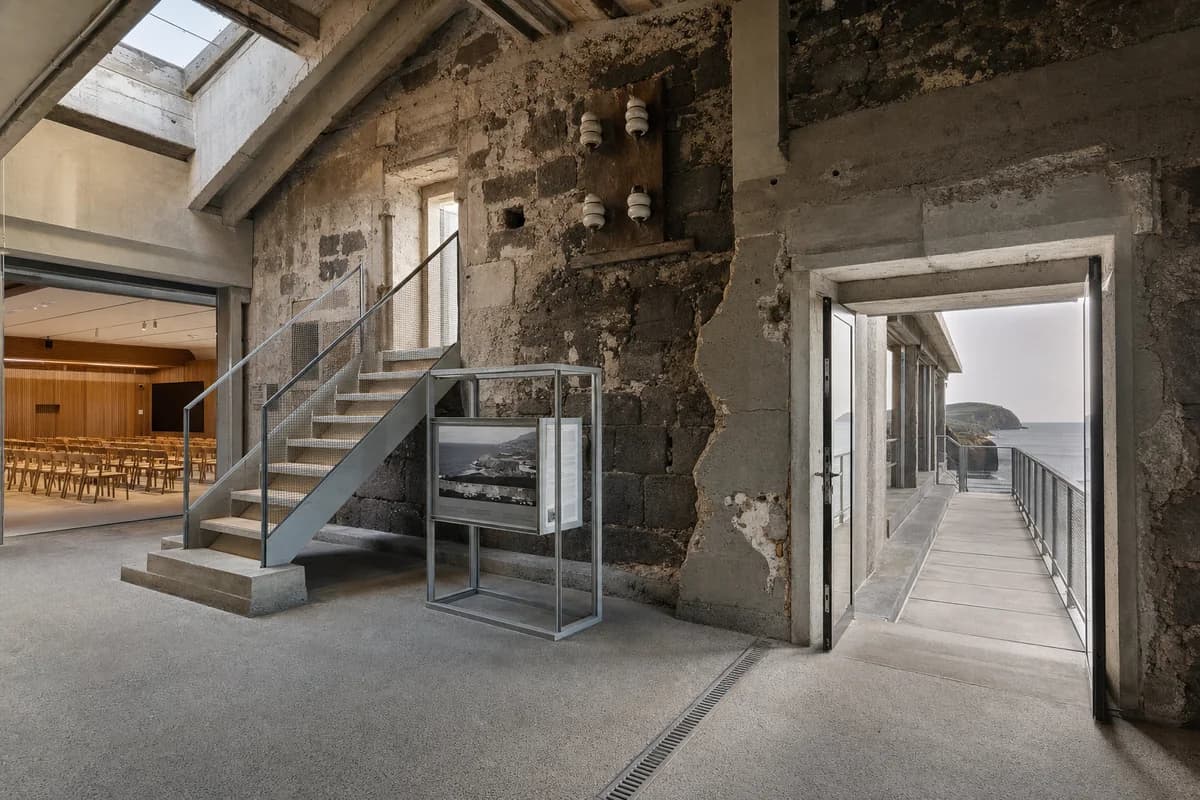 Unoccupied steel and timber observatory insertion inside a salt-softened basalt cable station.