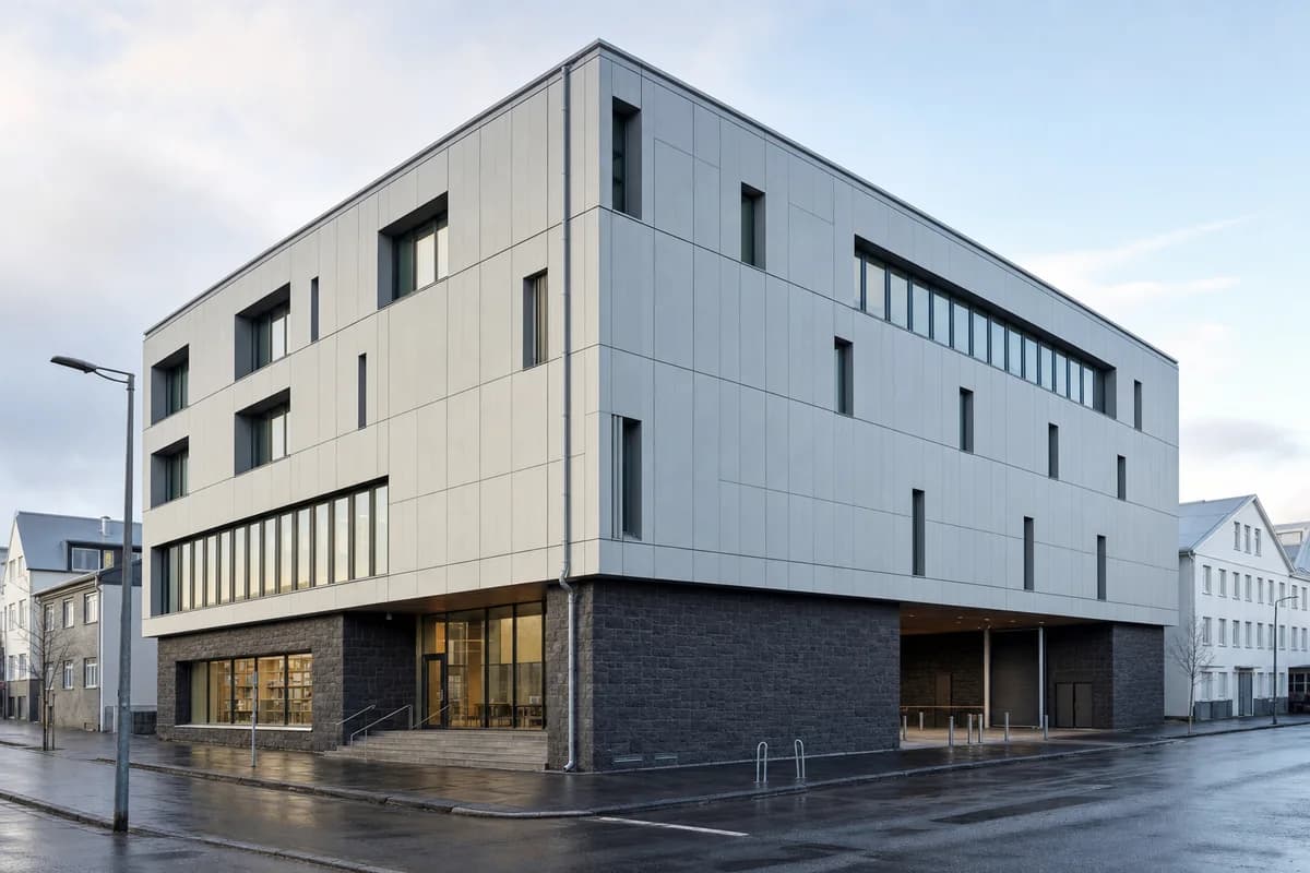 Opaque basalt and timber municipal archive with deep conservation bays on a wet Reykjavik street.