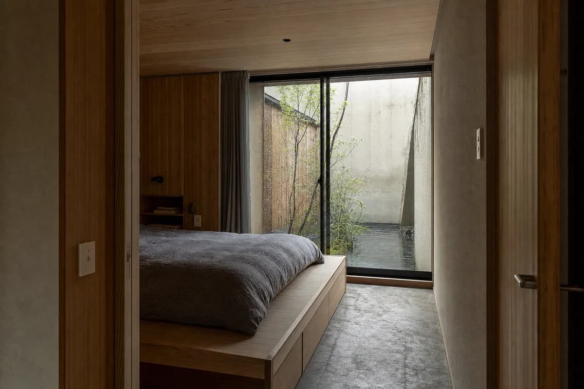 Rain-Court Bedroom, courtyard-house bedroom organized by a low sleeping platform facing a narrow weather court.