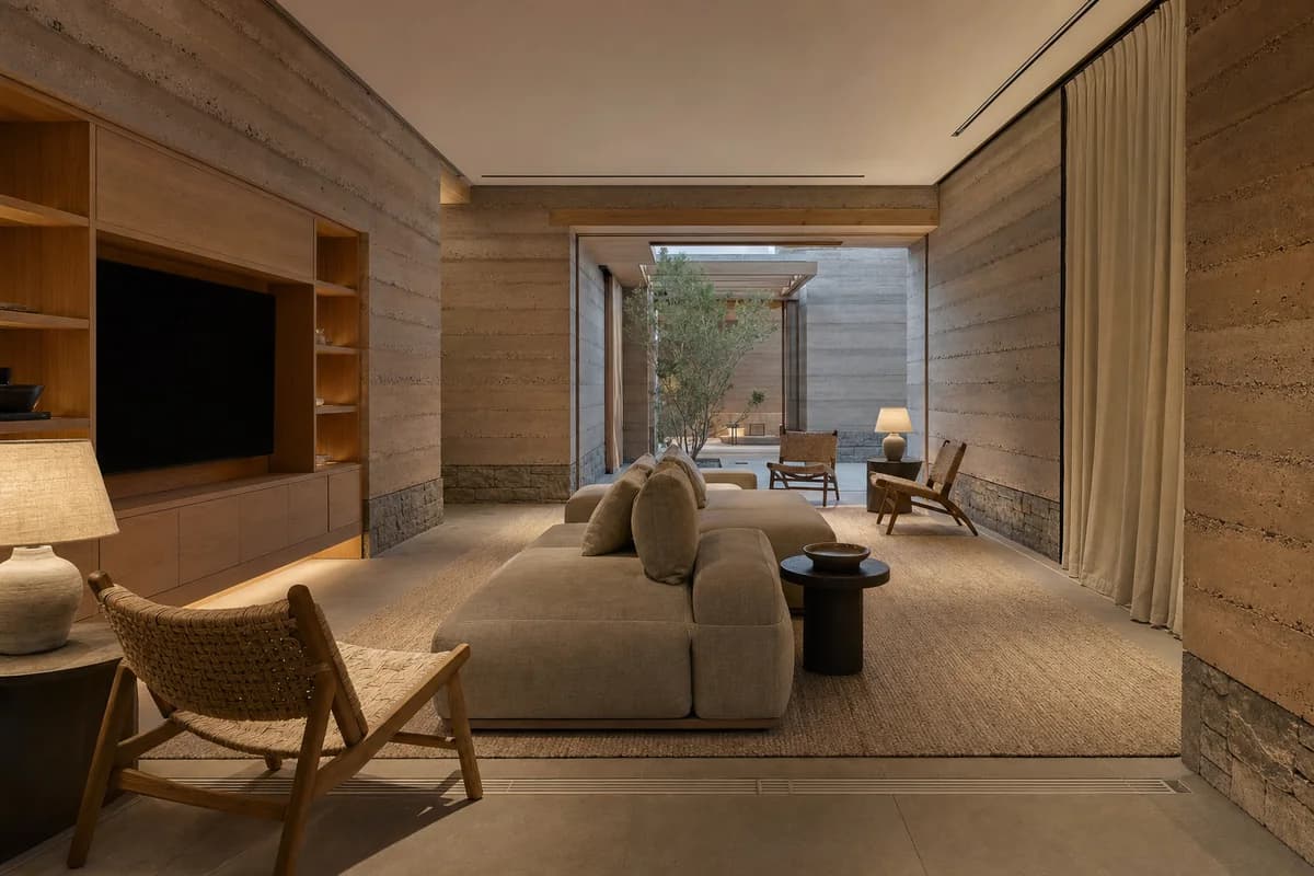 An unoccupied earth-walled listening lounge with low seating and warm lamps.