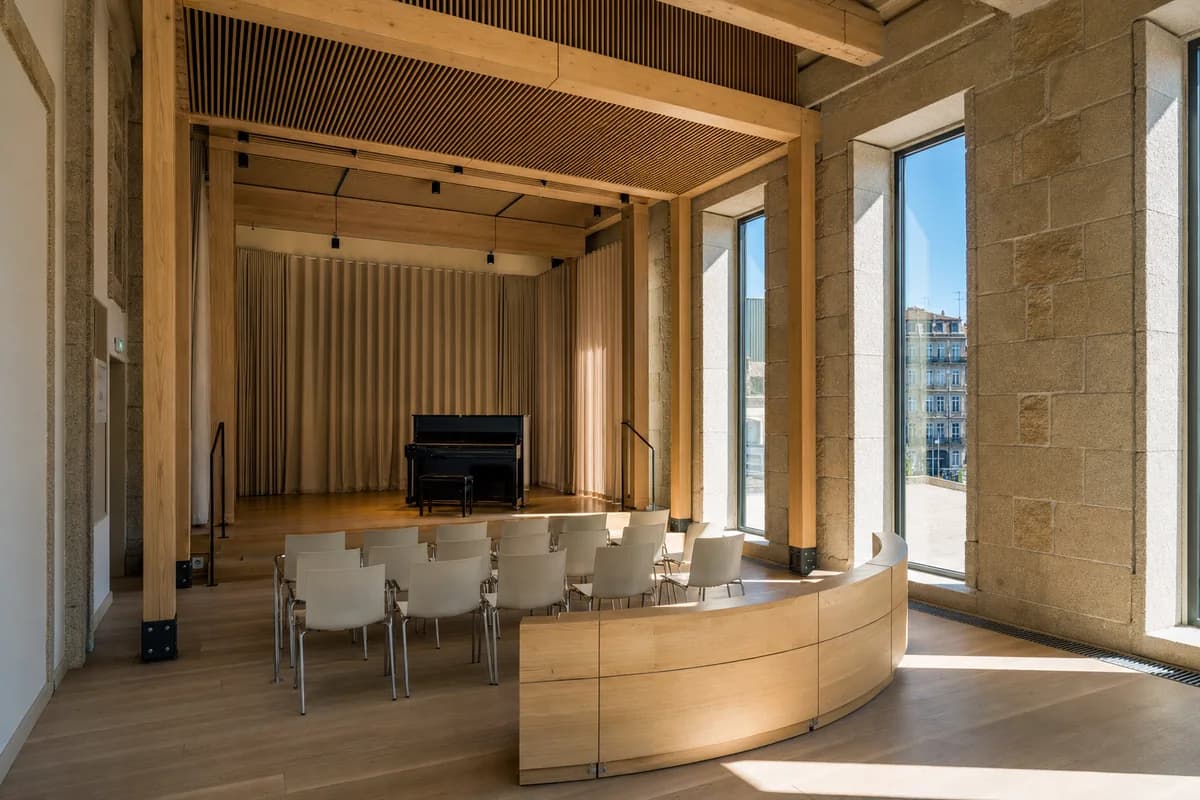An unoccupied Porto music salon receives strong warm sunlight through glazing beneath a clear blue sky.