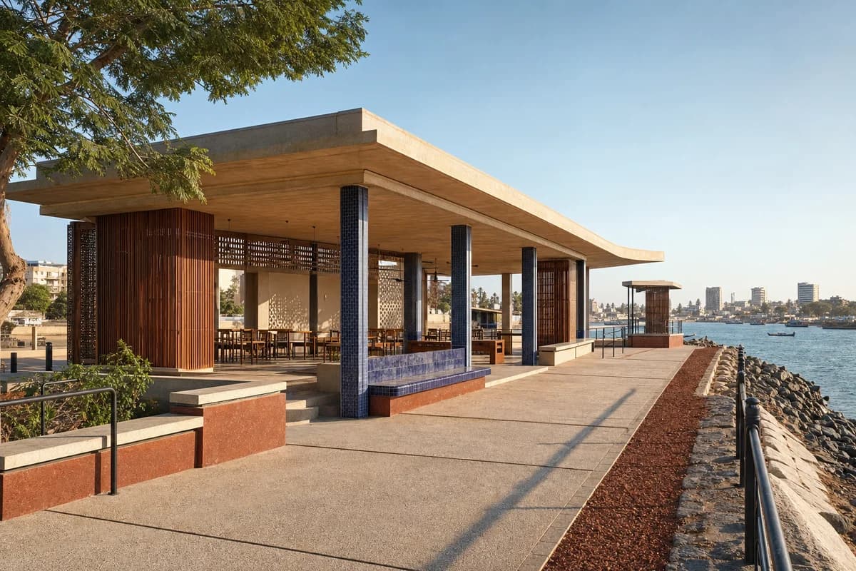 Unoccupied colorful Dakar harbor pavilion with indigo tile, iroko screens, and warm afternoon promenade light.