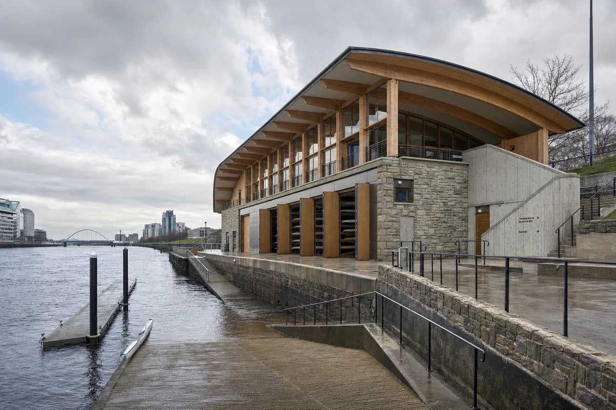 Glulam rowing hall and floodable stone apron beside the River Clyde.